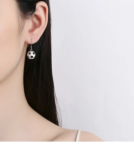Close-up of stylish 925 sterling silver soccer ball drop earrings worn on a female ear