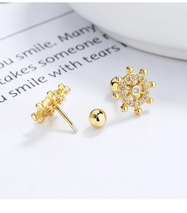 Detail of gold nautical wheel stud earrings in 925 sterling silver with zircon stones