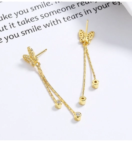 Macro shot of gold butterfly tassel earrings with cubic zirconia and long chains