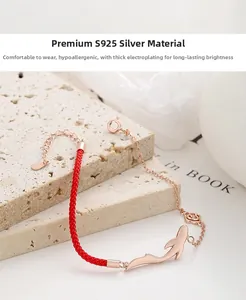 Detail of S925 sterling silver red woven bracelet with rose gold dolphin pendant charms