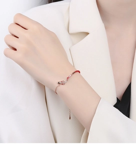 Detail of 925 sterling silver koi fish charm bracelet with red rope and rose gold finish