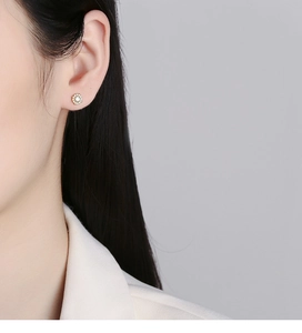 Detail of 925 silver flower stud earring with sparkling zircons on female model ear