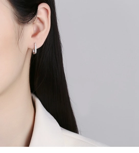Detail of model wearing a 925 sterling silver U-shaped earring with zircon micro-pave