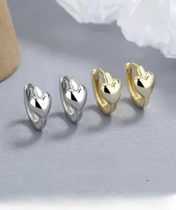 Vue macro de boucles d'oreilles créoles cœur en argent 925 et or avec finition miroir