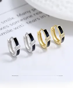 Détail de boucles d'oreilles en argent S925 et or avec émail noir et pierres zircon