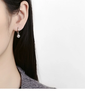 Gros plan de boucles d'oreilles créoles en argent 925 avec zircons carrés portées à l'oreille