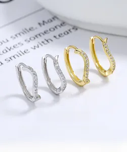 Detailed macro view of S-shaped silver hoop earrings with pavé zircons in gold and silver