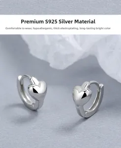 Gros plan de boucles d'oreilles cœur en argent sterling S925 poli sur fond minimaliste