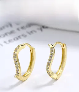 Detailed close-up of golden wavy S925 sterling silver earrings with inlaid zircon stones