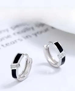 Détail macro de boucles d'oreilles en argent 925 avec émail noir et trois petits zircons
