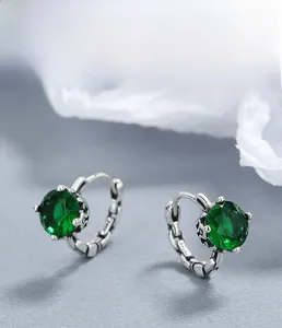 Macro detail of S925 sterling silver emerald earrings with hollow carved vintage texture