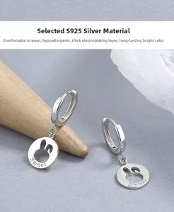 Macro detail of S925 sterling silver rabbit earrings with Sweet engraving on grey texture