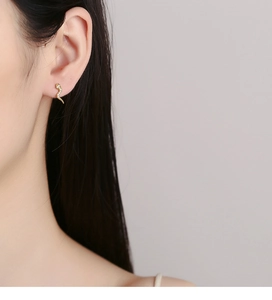 Model wearing gold snake stud earring with zircon stones on the ear cartilage