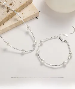 Detail of 925 silver necklace and bracelet set with freshwater pearls on stone surface