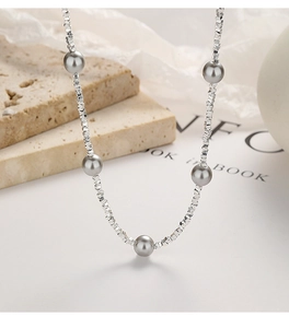 Detail of 925 silver beaded necklace with grey pearls on a stone background