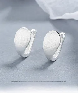 Macro view of teardrop S925 silver hoop earrings with a brushed matte finish texture
