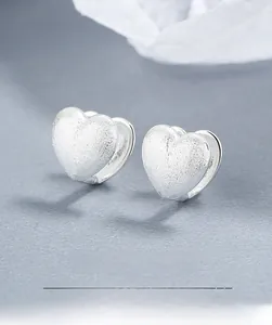 Detail view of double heart hoop earrings with brushed silver matte finish and secure buckle