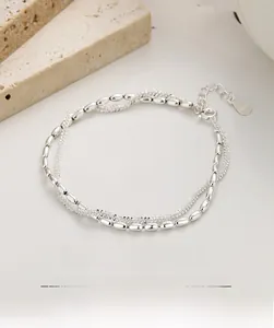 Macro shot of double-layer 925 sterling silver bracelet with rice beads and heart tag