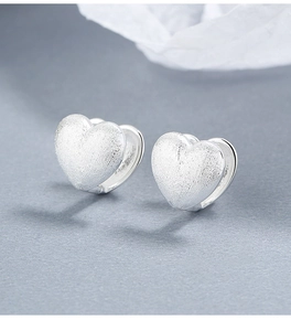 Detailed macro view of S925 sterling silver heart earrings with matte and polished texture