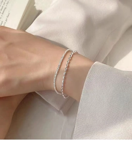 Detail of a layered 925 sterling silver bracelet with starry texture and oval beads