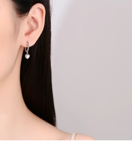 Close-up of 925 silver heart moonstone hoop earring with twisted texture on model