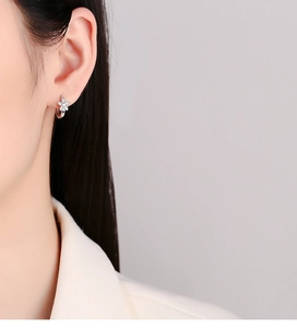 Detailed view of sterling silver flower earrings with small zircon stones on model's ear