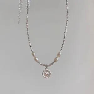 Detail of silver beaded necklace with freshwater pearls and a golden heart pendant