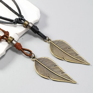 Vintage bronze leaf pendant necklaces with adjustable leather cords on marble stone