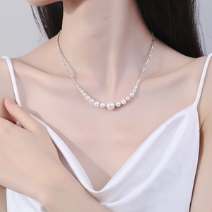 Detail of elegant gradient pearl necklace on a model wearing white satin dress