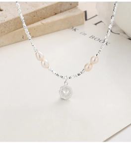 Detailed close-up of 925 silver beaded necklace featuring a heart charm and natural pearls
