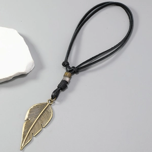 Detailed macro view of the vintage bronze feather pendant and black leather cord necklace