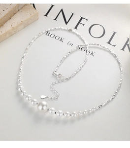 Detail of 925 silver necklace with gradient pearls and faceted beads on a book