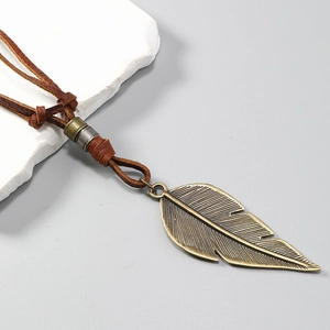 Detailed close-up of retro bronze feather pendant on adjustable brown leather cord necklace