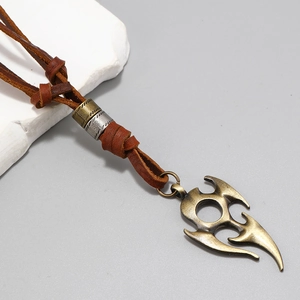 Detail of vintage bronze tribal pendant with textured metal and brown braided leather cord