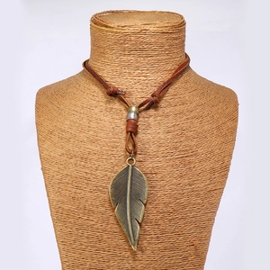 Detailed close-up of vintage bronze feather pendant on adjustable brown leather cord necklace