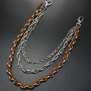 Détail d'une chaîne de pantalon à trois rangs en métal argenté et cuir marron tressé