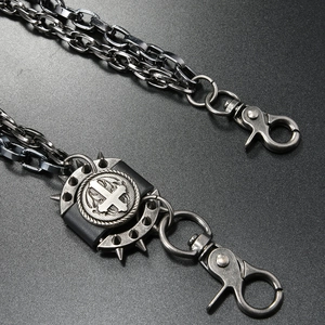 Detail of gothic punk trousers chain with spiked inverted cross medal and metal links