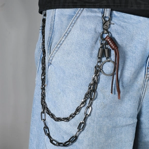 Detail view of multi-layer gunmetal chains with dark brown leather tassels on denim