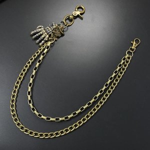 Détail d'une chaîne de pantalon punk à deux couches en bronze avec crâne et mains
