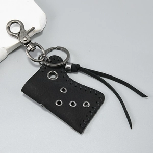 Detail of vintage black leather lighter case with metallic carabiner and rustic fringe