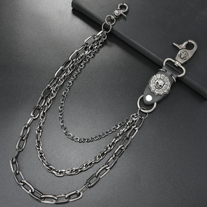 Detailaufnahme der mehrlagigen Metall-Hosenkette mit Totenkopf-Emblem und Leder