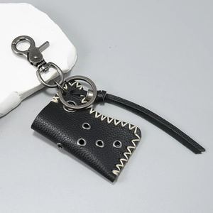 Detail of black leather lighter holster with vintage silver swivel clasp and white stitching