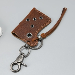 Macro detail of dark brown leather lighter sleeve with manual stitching and metal carabiner
