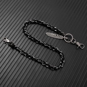 Detail of punk hip-hop wallet chain featuring woven leather, metal links and feather charm