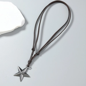 Dettaglio di un ciondolo a stella vintage in argento scuro su cordino marrone regolabile
