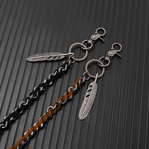 Detail of punk style braided leather trousers chain with vintage silver feather pendants
