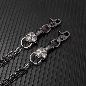 Detail of gothic punk waist chain with skull lobster clasp and cross medal on dark surface