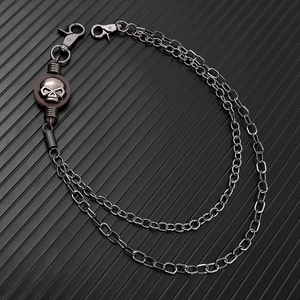 Detail of punk double-layer metal wallet chain featuring a skull emblem and lobster clasps