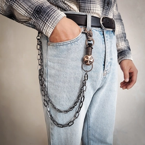 Detail of layered punk hip-hop wallet chain with skull and cross charms on denim pants