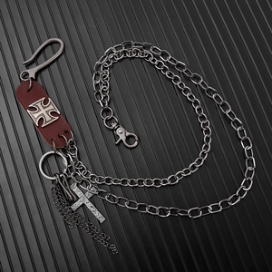 Détail d'une chaîne de pantalon punk multicouche avec patch en cuir et pendentif croix rétro